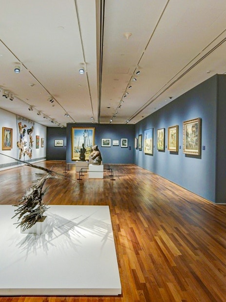 National Gallery Singapore interior with diverse art exhibits displayed on walls and sculptures on the floor.