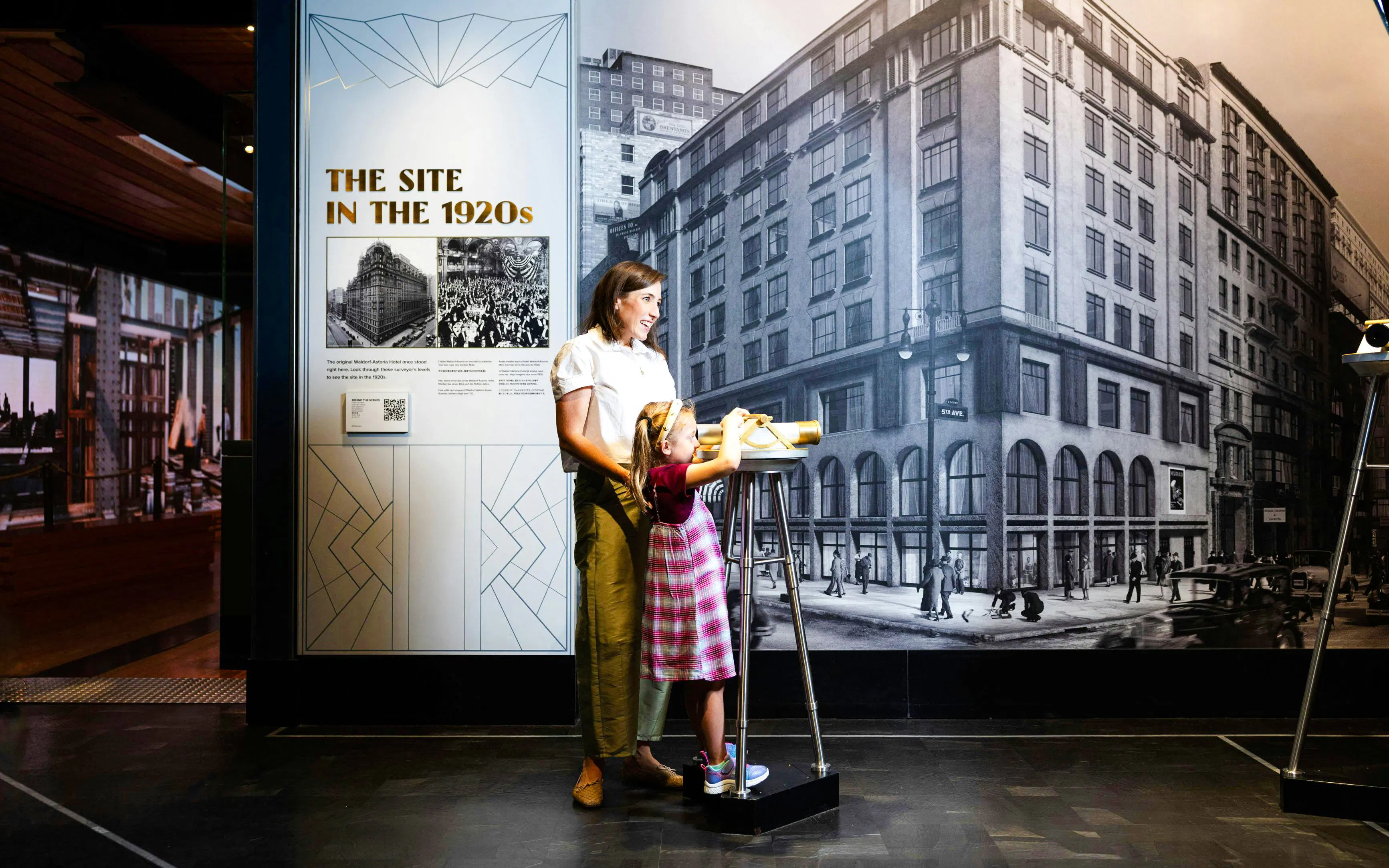 Mother and child viewing Empire State Building exhibit on 1920s site history.