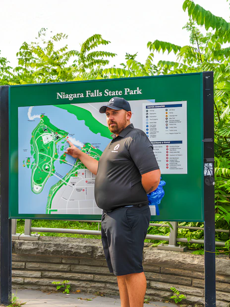 Family learning about Niagara Falls at a park map with a guide.