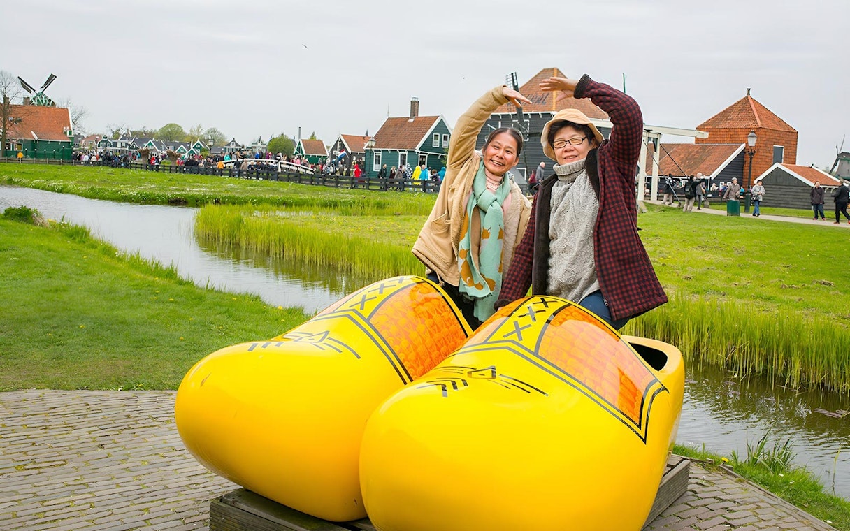 Visitors posing with giant clogs at Zaanse Schans Windmill Village near Amsterdam.