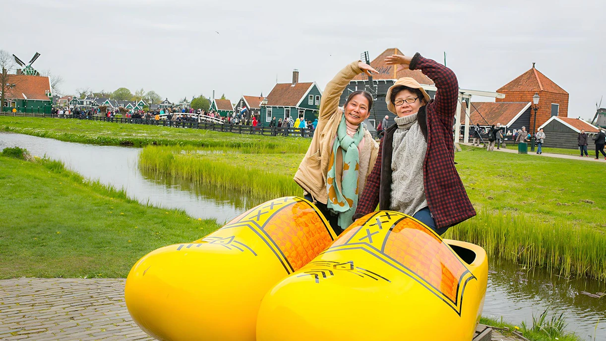 Visitors posing with giant clogs at Zaanse Schans Windmill Village near Amsterdam.