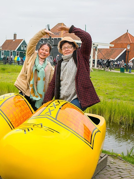 Visitors posing with giant clogs at Zaanse Schans Windmill Village near Amsterdam.