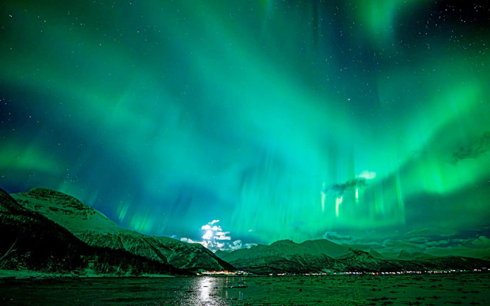 Northern Lights over snowy mountains in Tromso during a small group chase tour.