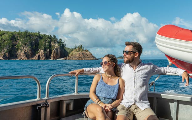 Couple enjoying boat ride on Outer Reef Snorkel Adventure with island view.