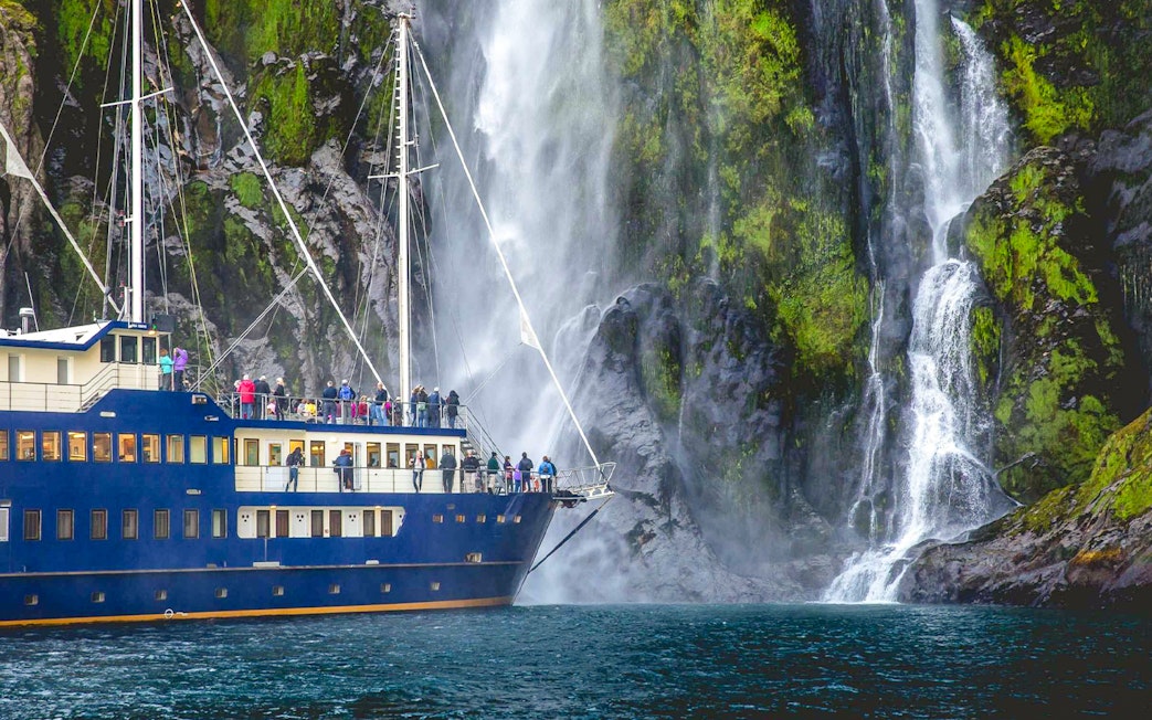 Ship passengers viewing waterfall in Milford Sound, New Zealand.