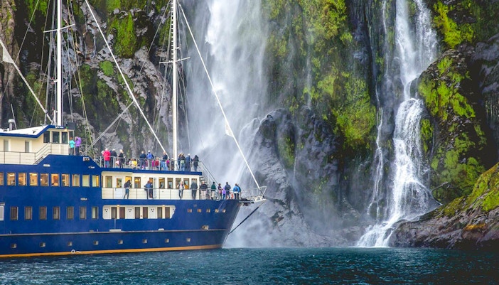 People on a ship looking at a waterfall in Milford Sound