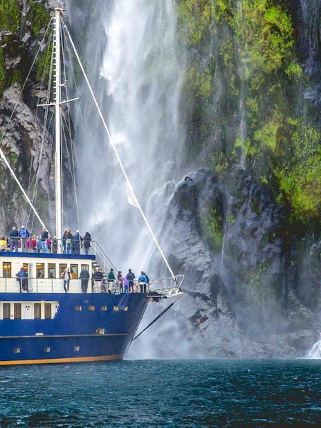 Ship passengers viewing waterfall in Milford Sound, New Zealand.