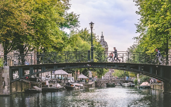 Canal bridge with cyclists in Amsterdam, Netherlands, viewed from a luxury canal cruise.