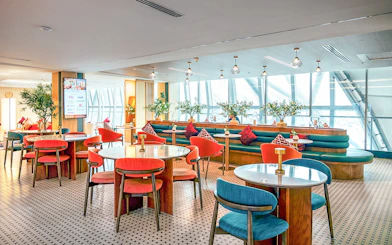 Coral Airport Lounge seating area at Suvarnabhumi Airport with tables and chairs.