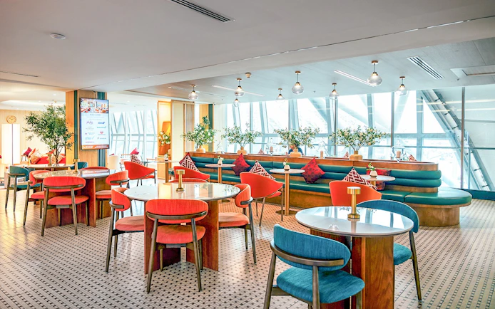 Coral Airport Lounge seating area at Suvarnabhumi Airport with tables and chairs.