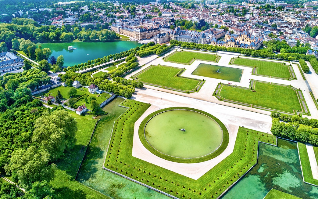 Aerial view of the Palace of Fontainebleau Gardens with geometric lawns and a central pond.