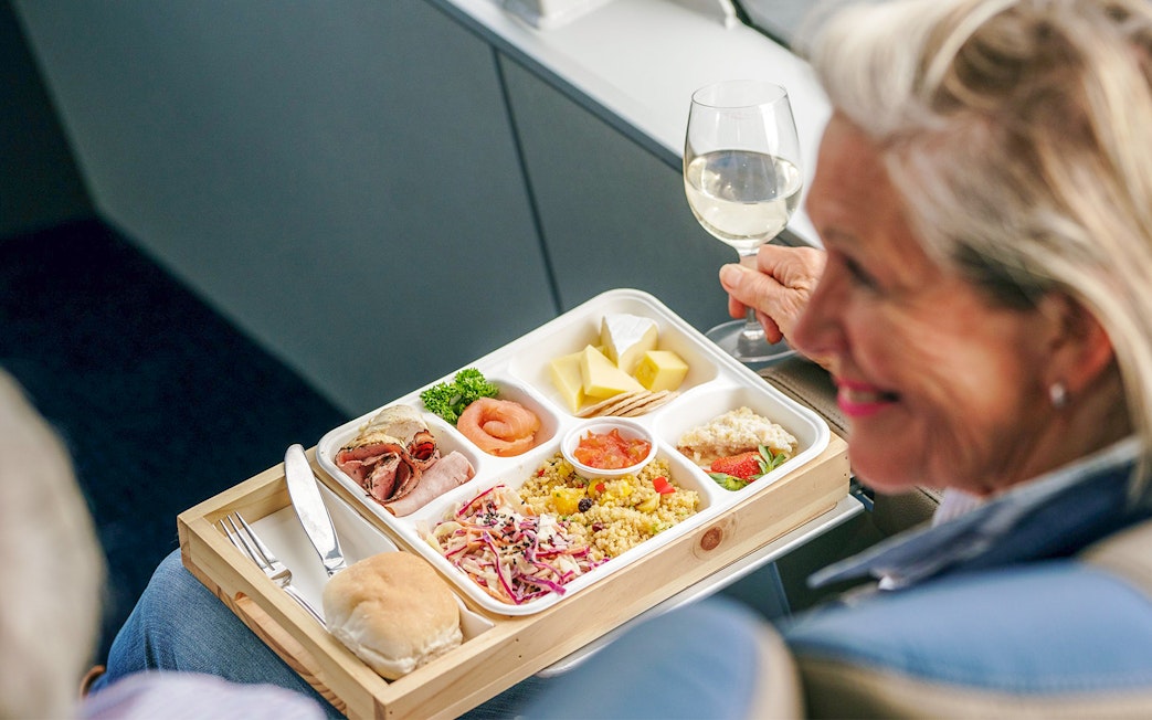 Salmon and assorted lunch on a cruise with a person holding a glass of wine.