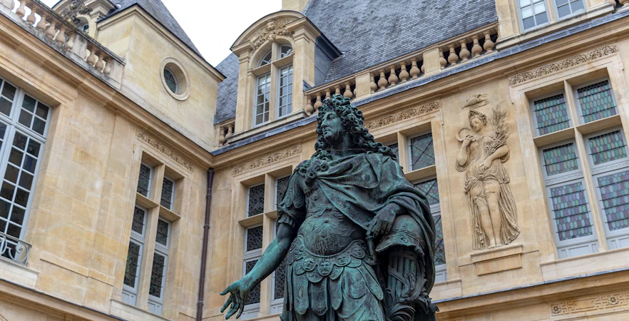 Sculpture of Louis XIV at Musée Carnavalet, Paris, with ornate building facade.