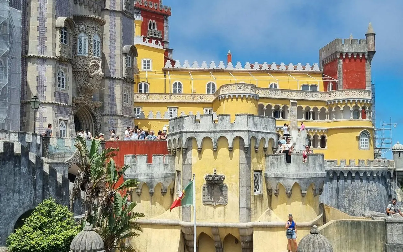 Pena Palace in Sintra with tourists exploring the colorful architecture.