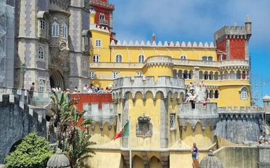 Pena Palace in Sintra with tourists exploring the colorful architecture.