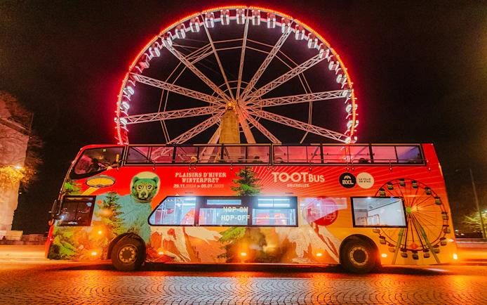 Brussels Christmas hop-on hop-off bus with illuminated Ferris wheel at night.
