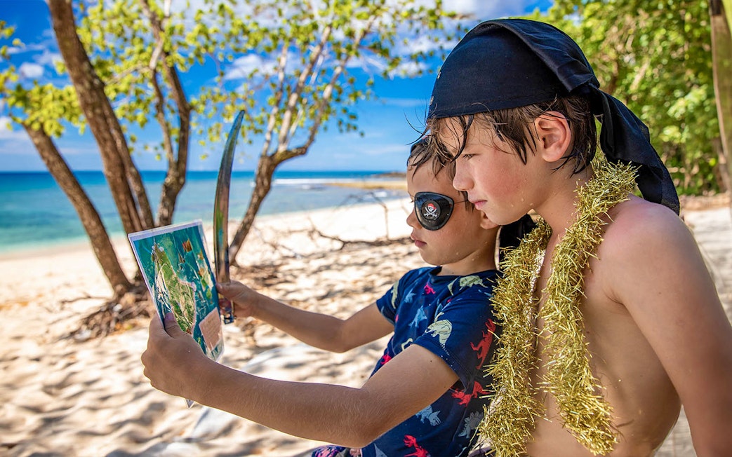 Boys dressed as pirates studying map on Frankland Islands beach.
