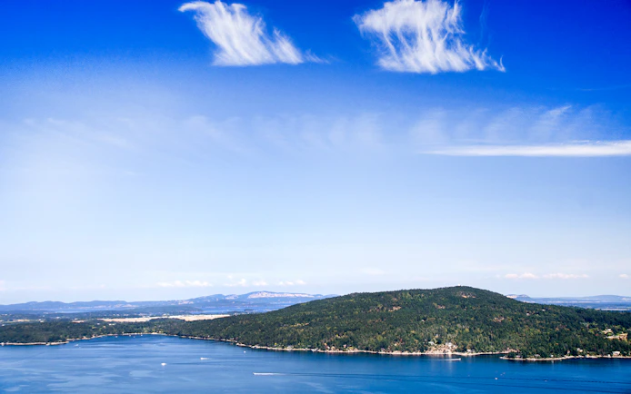 Panoramic view of Saanich Inlet with lush green hills and blue sky.