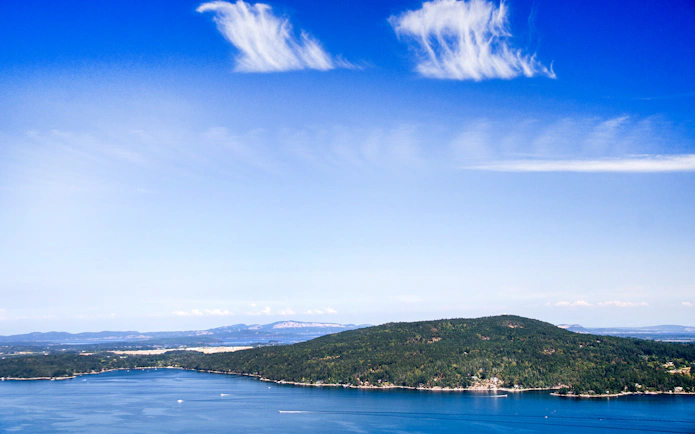 Panoramic view of Saanich Inlet with lush green hills and blue sky.