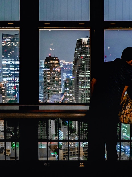 Couple enjoying Tokyo cityscape at night from Tokyo Tower observation deck.