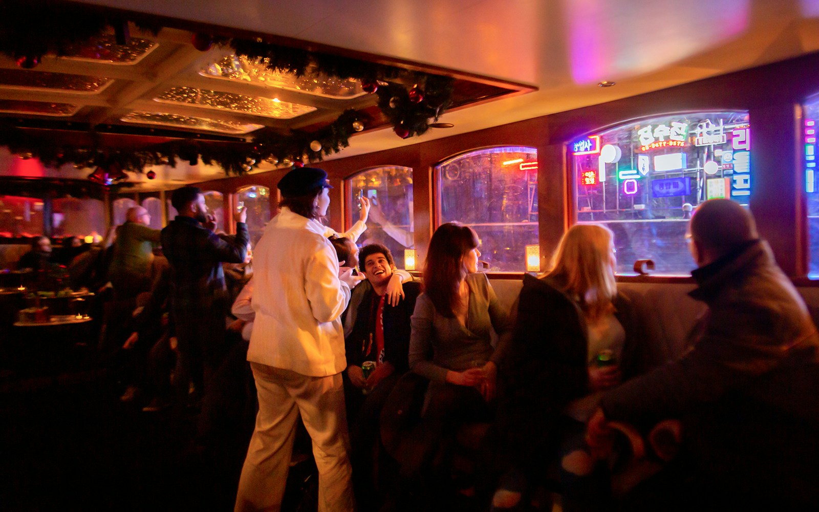 Guests enjoying the Amsterdam Light Festival Cruise with neon lights outside.