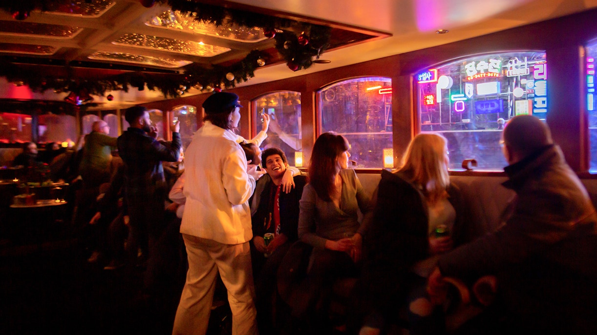 Guests enjoying the Amsterdam Light Festival Cruise with neon lights outside.