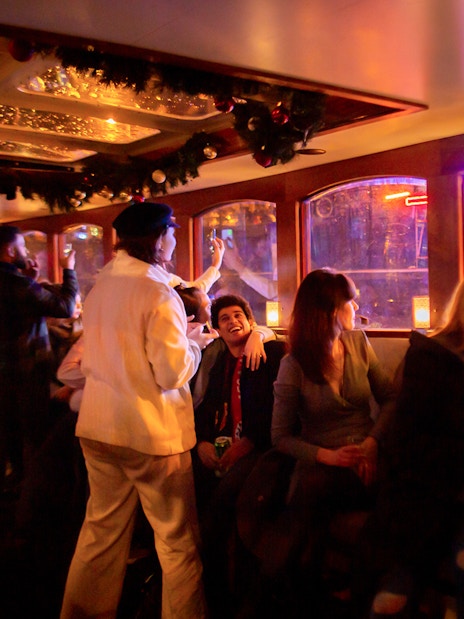 Guests enjoying the Amsterdam Light Festival Cruise with neon lights outside.