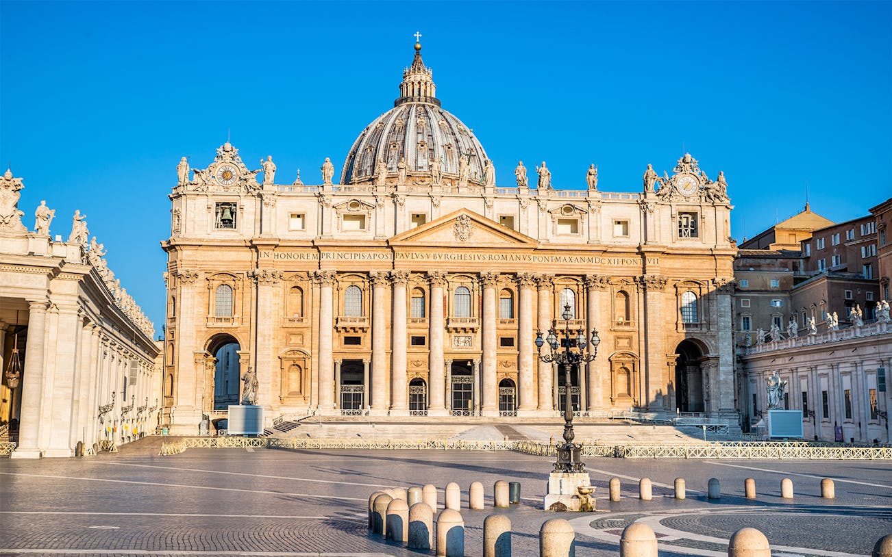 St. Peter's Basilica facade in Vatican City with clear blue sky.