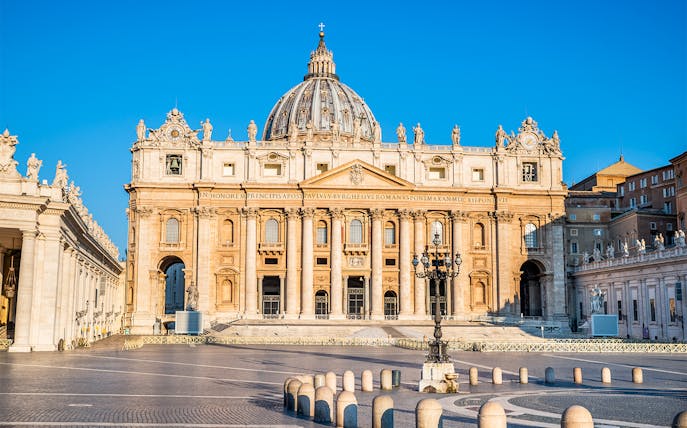 St. Peter's Basilica facade in Vatican City with clear blue sky.