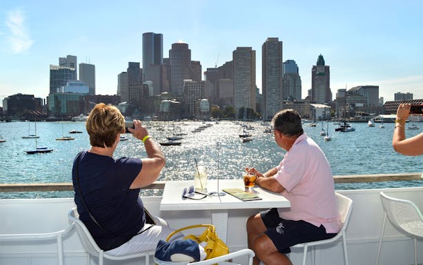 People enjoying views of Boston skyline from a lunch cruise on the harbor.