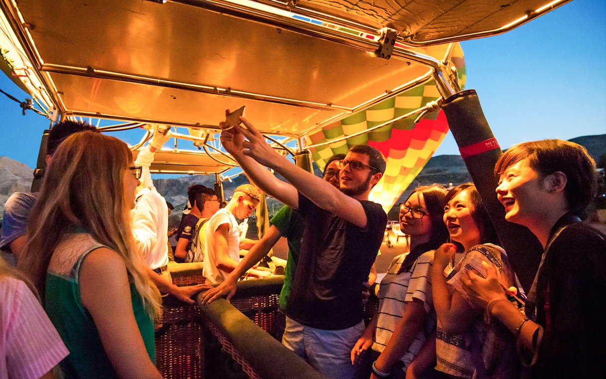 Group of people preparing for a hot air balloon ride at sunset.