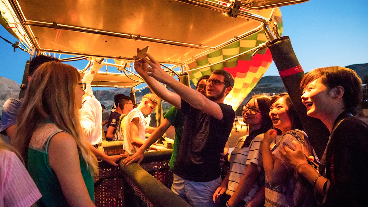 Group of people preparing for a hot air balloon ride at sunset.