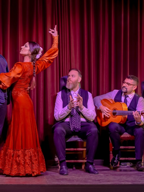 Flamenco dancers performing at Palau Dalmases with musicians and audience clapping.