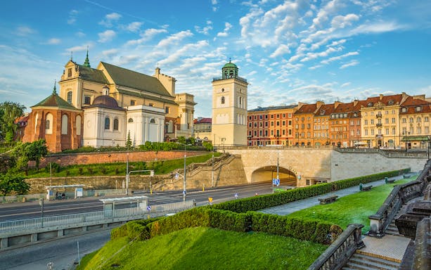 Warsaw Old Town buildings and church viewed from a park, part of guided tour with hotel transfers.
