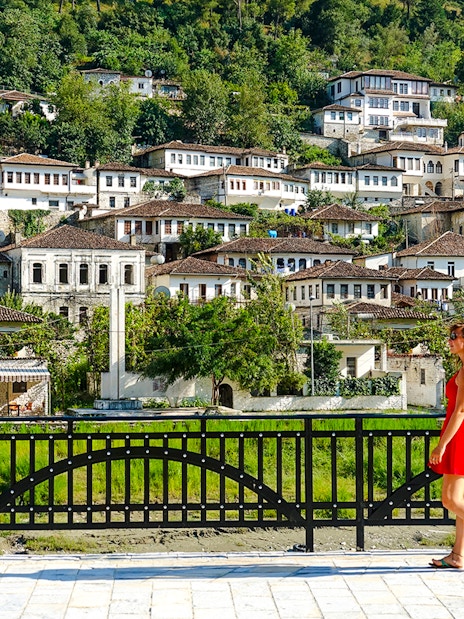 Guest walking in front of traditional Ottoman houses in Berat old town, Albania.