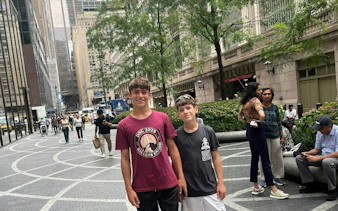New York City street scene with people walking and skyscrapers in the background.