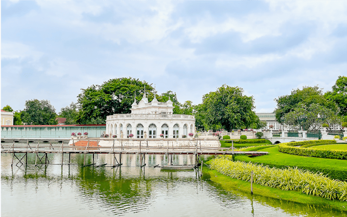 Bang Pa In Palace pavilion with arched windows and surrounding gardens reflected in a pond.