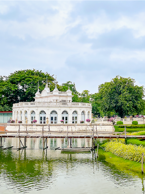 Bang Pa In Palace pavilion with arched windows and surrounding gardens reflected in a pond.
