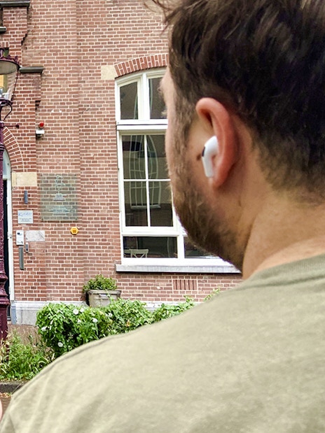 Guest using mobile guide outside Kinder Garden building on Anne Frank tour, Amsterdam.