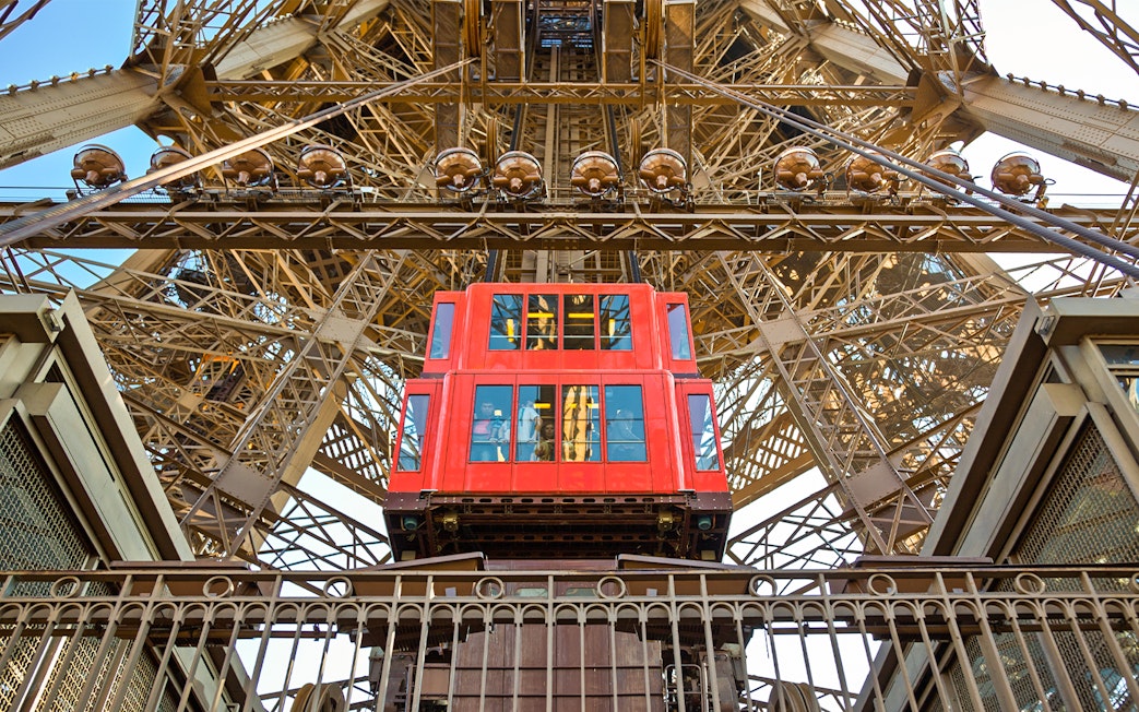 Red elevator ascending inside the Eiffel Tower, Paris.