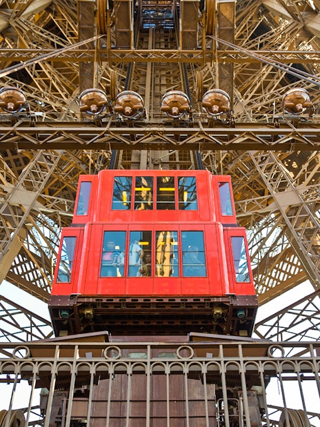 Red elevator ascending inside the Eiffel Tower, Paris.
