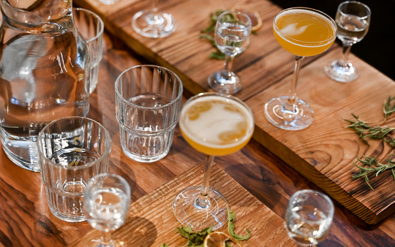 Vodka tasting setup at Krakow museum with glasses and herbs on wooden table.