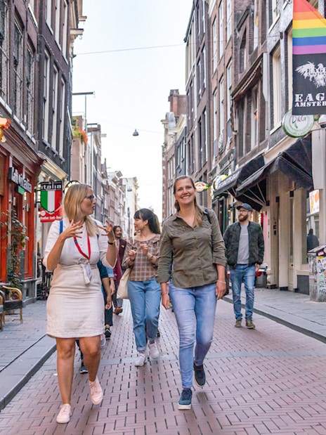 Tour group walking through Amsterdam's Red Light District with guide, near coffeeshops.