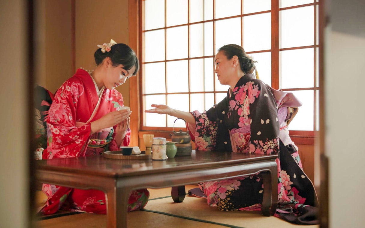 Licensed tea master instructing guest on matcha whisking near Kyoto’s Golden Pavilion.
