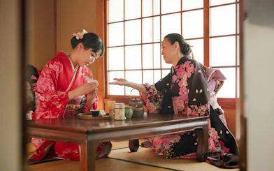 Licensed tea master instructing guest on matcha whisking near Kyoto’s Golden Pavilion.