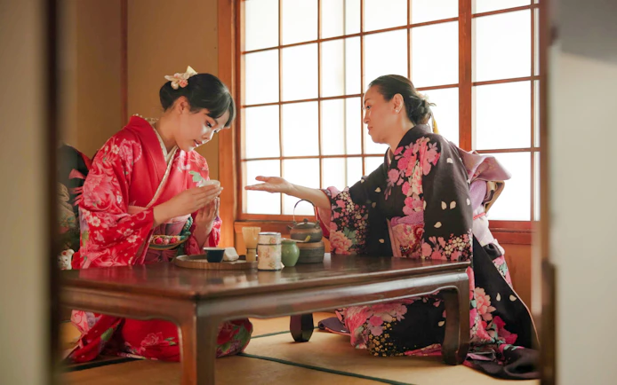 Licensed tea master instructing guest on matcha whisking near Kyoto’s Golden Pavilion.