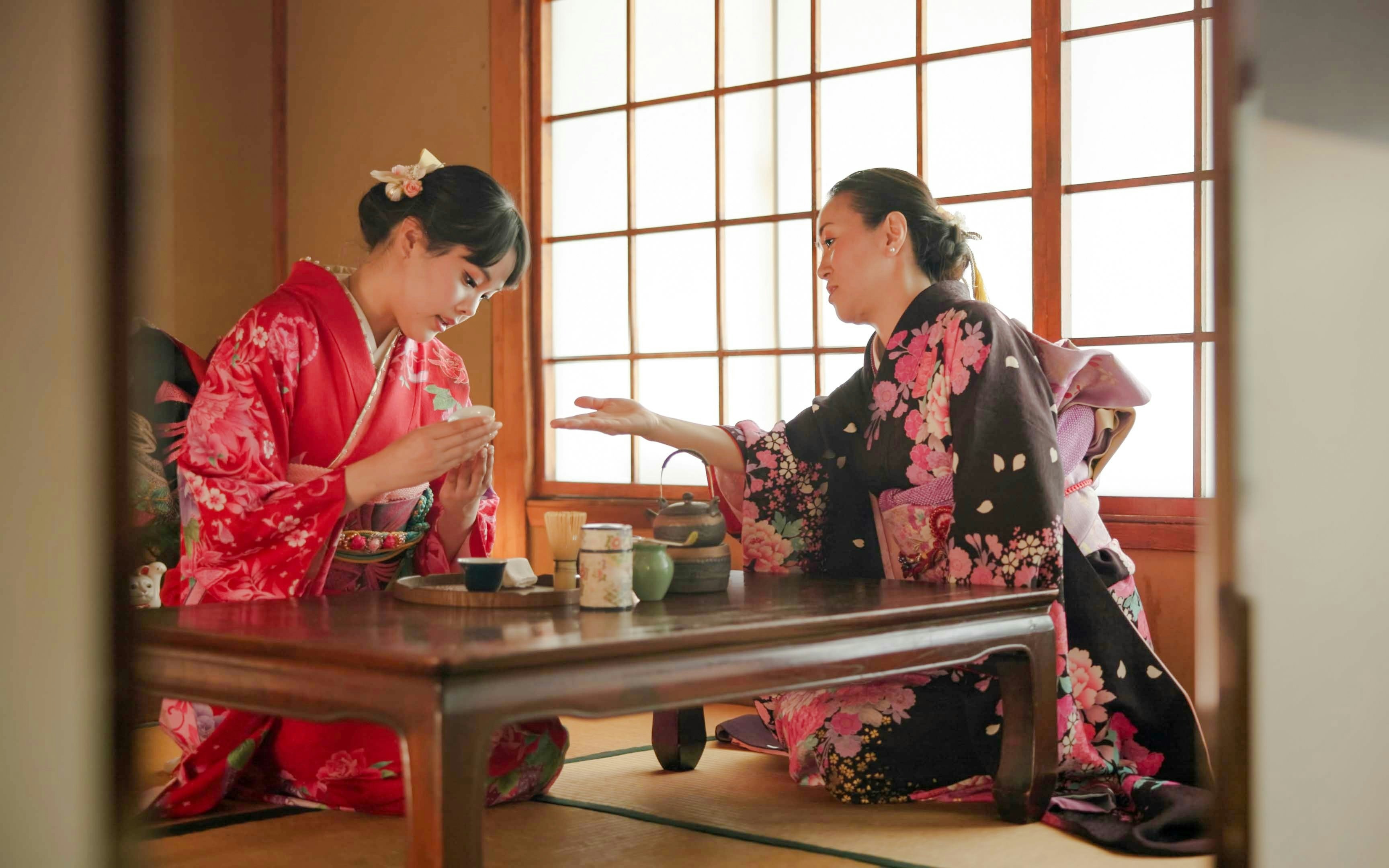 Licensed tea master instructing guest on matcha whisking near Kyoto’s Golden Pavilion.