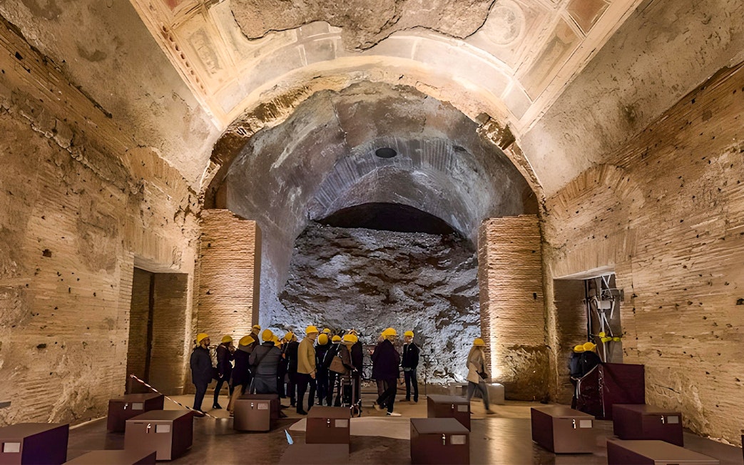 Visitors with helmets exploring Domus Aurea's ancient ruins in Rome.