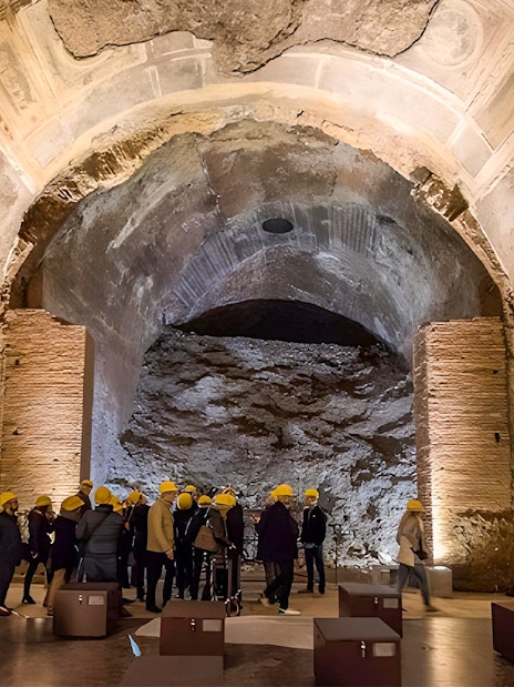 Visitors with helmets exploring Domus Aurea's ancient ruins in Rome.