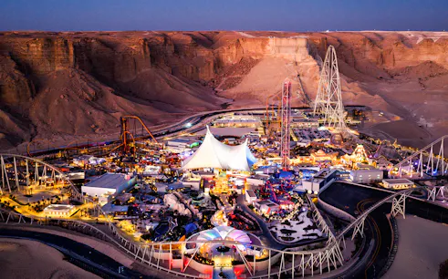 Aerial view of Six Flags Qiddiya City amusement park with roller coasters and attractions.